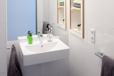 Badezimmer mit Waschbecken, Toilette und Fenster mit Pflanze.